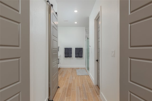 hall with light hardwood / wood-style floors and a barn door