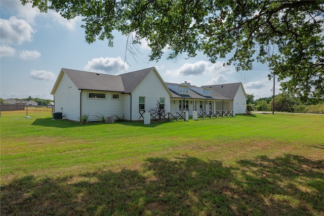 rear view of property with central AC and a lawn