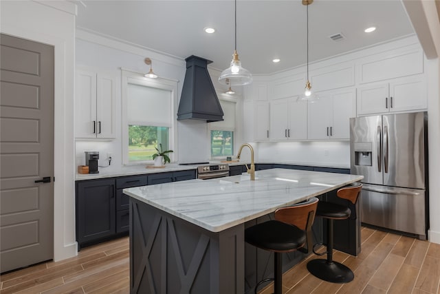 kitchen featuring appliances with stainless steel finishes, white cabinets, and an island with sink