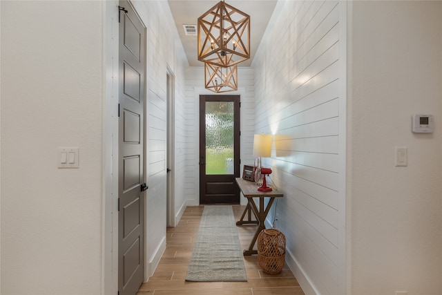 doorway featuring a notable chandelier and light wood-type flooring