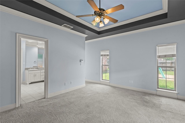 unfurnished room featuring ornamental molding, light colored carpet, a raised ceiling, and ceiling fan