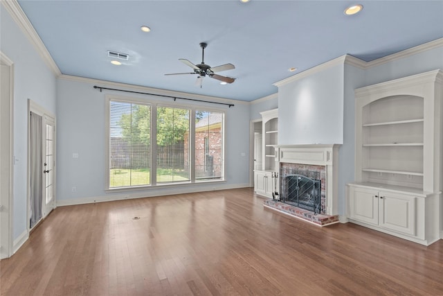 unfurnished living room with a premium fireplace, wood-type flooring, built in features, and crown molding