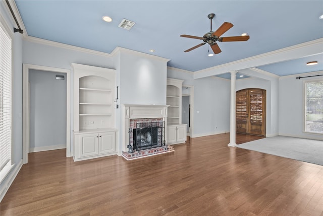 unfurnished living room with built in features, a fireplace, wood-type flooring, ceiling fan, and crown molding