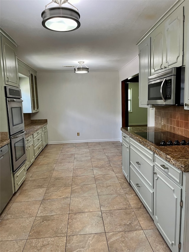 kitchen with light tile patterned flooring, decorative backsplash, stainless steel appliances, and dark stone countertops