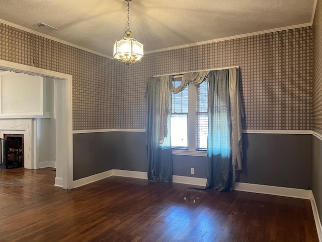 unfurnished dining area featuring a textured ceiling, ornamental molding, a fireplace, and dark wood-type flooring