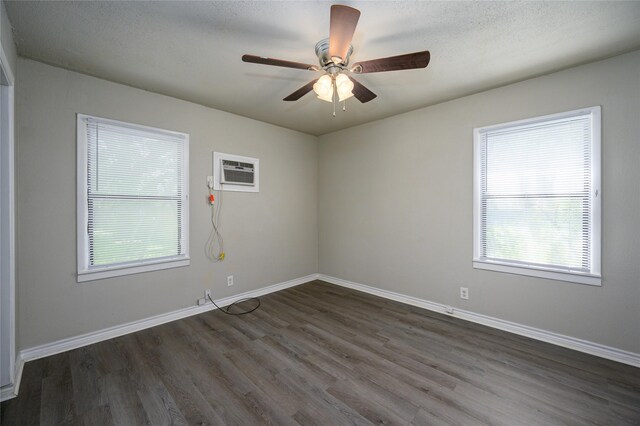 unfurnished room featuring an AC wall unit, ceiling fan, and dark wood-type flooring