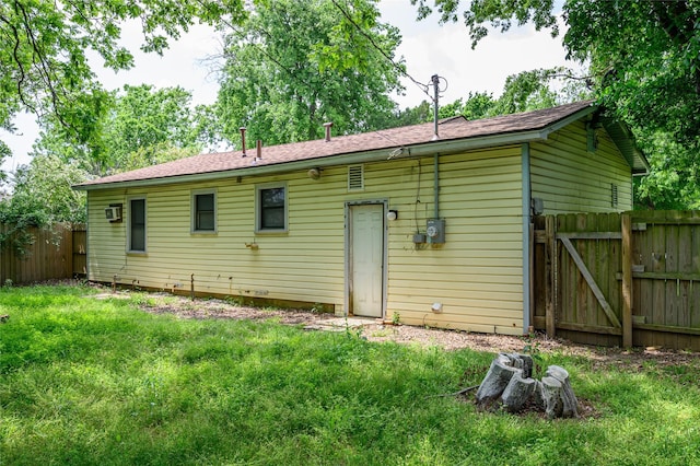 rear view of house with a wall mounted air conditioner and a lawn