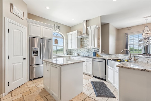 kitchen with white cabinetry, tasteful backsplash, wall chimney range hood, a center island, and appliances with stainless steel finishes