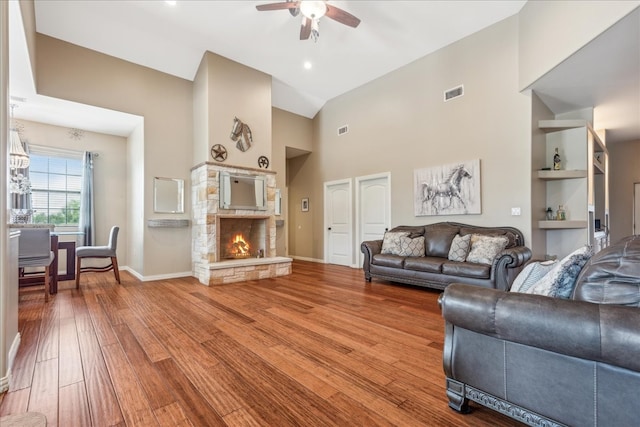 living room with a fireplace, ceiling fan, built in shelves, high vaulted ceiling, and hardwood / wood-style floors