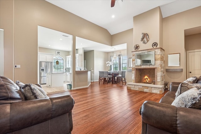 living room featuring a stone fireplace, light hardwood / wood-style flooring, and ceiling fan