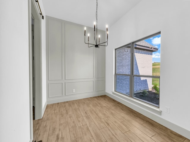 unfurnished dining area featuring light hardwood / wood-style floors and a notable chandelier