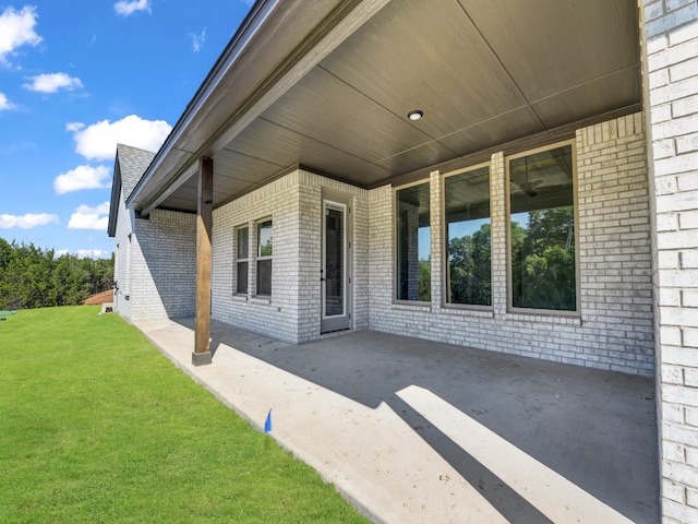 view of exterior entry featuring a yard and a patio area