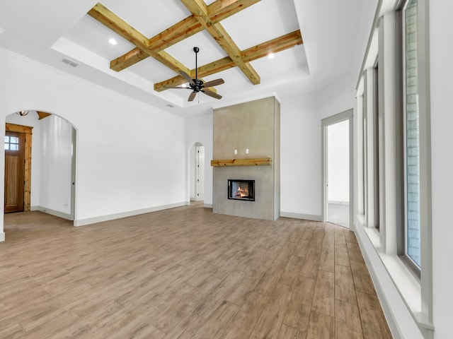 unfurnished living room featuring a fireplace, plenty of natural light, light hardwood / wood-style floors, and coffered ceiling