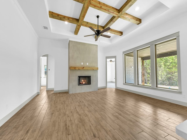 unfurnished living room featuring beamed ceiling, ceiling fan, a fireplace, coffered ceiling, and light hardwood / wood-style flooring