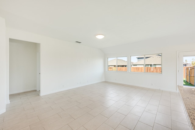 unfurnished room with lofted ceiling and light tile patterned flooring