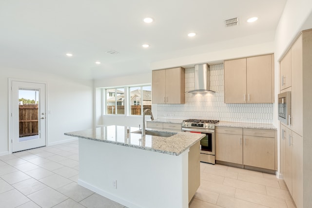 kitchen featuring wall chimney exhaust hood, sink, light brown cabinets, and appliances with stainless steel finishes