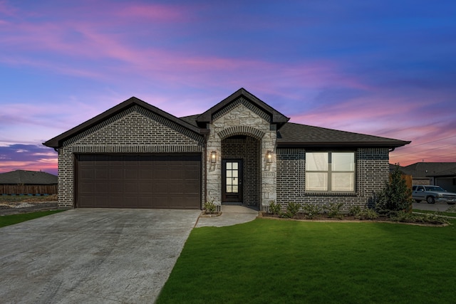 french country inspired facade featuring a lawn and a garage