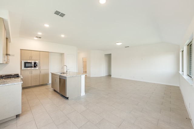 kitchen featuring light stone countertops, light brown cabinetry, sink, stainless steel appliances, and a center island with sink