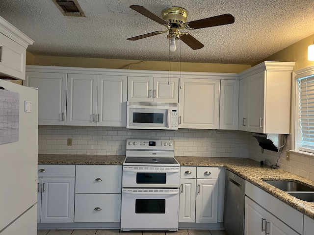 kitchen featuring decorative backsplash, white appliances, light tile patterned floors, and white cabinets