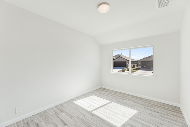 spare room featuring light hardwood / wood-style flooring and vaulted ceiling