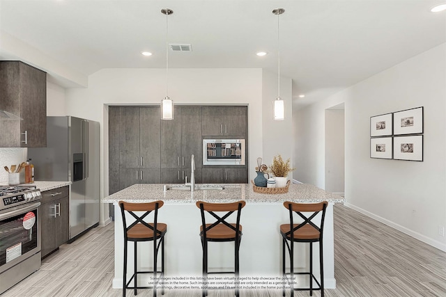 kitchen featuring a breakfast bar, stainless steel appliances, a center island with sink, and sink