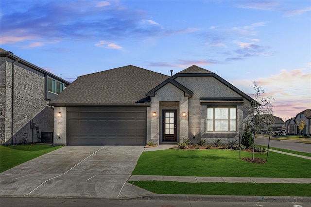 french country home featuring a garage and a yard