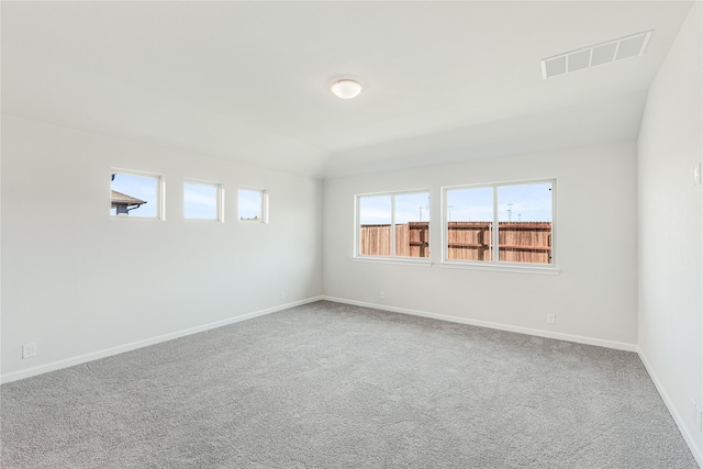 carpeted empty room featuring lofted ceiling