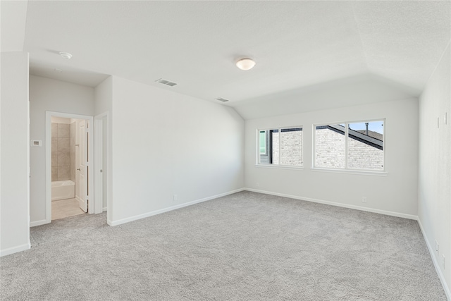 carpeted spare room featuring lofted ceiling