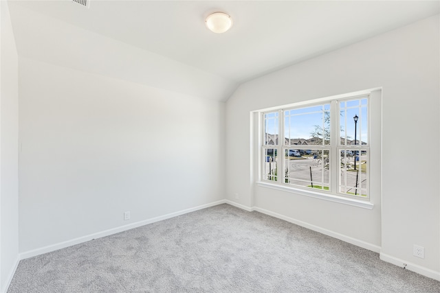 carpeted spare room featuring lofted ceiling