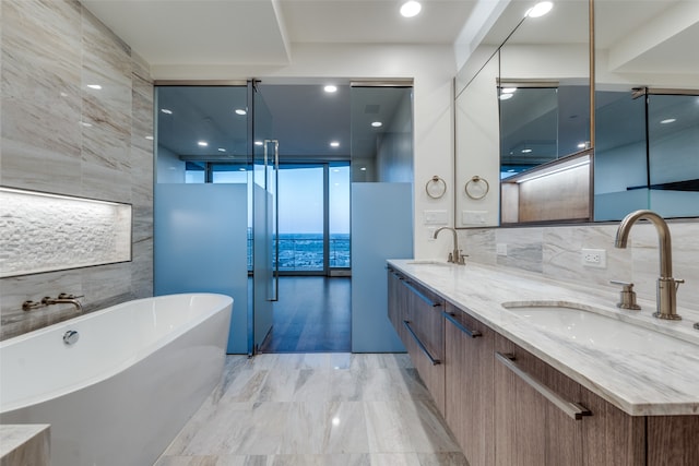 bathroom featuring double vanity, tile walls, a tub to relax in, and tile patterned floors