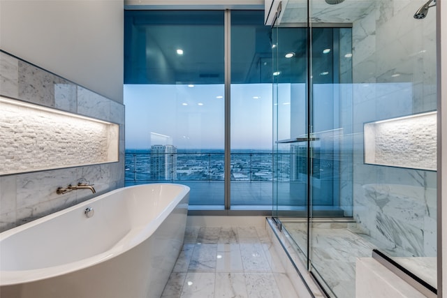 bathroom featuring plus walk in shower, tile patterned flooring, and tile walls