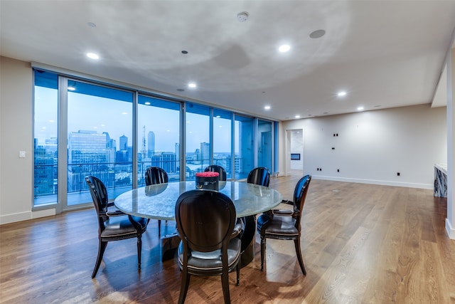 dining area featuring wood-type flooring and a wall of windows