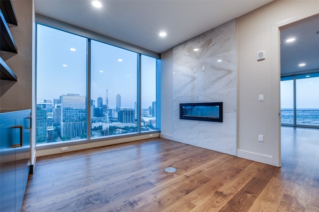 unfurnished living room featuring a fireplace, hardwood / wood-style floors, expansive windows, and plenty of natural light