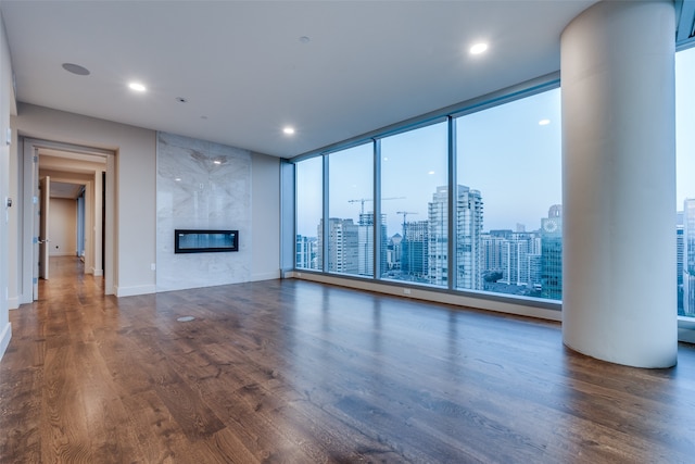 unfurnished living room featuring dark wood-type flooring, floor to ceiling windows, and a fireplace