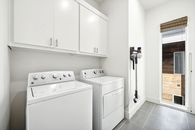 clothes washing area with separate washer and dryer, cabinets, and dark tile patterned floors