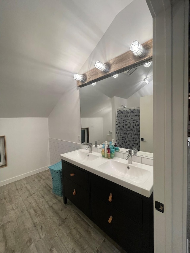 bathroom featuring vanity, vaulted ceiling, tile walls, and wood-type flooring