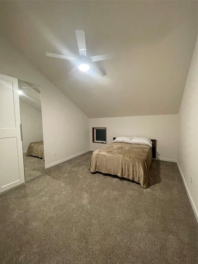 unfurnished bedroom with ceiling fan, dark carpet, and lofted ceiling