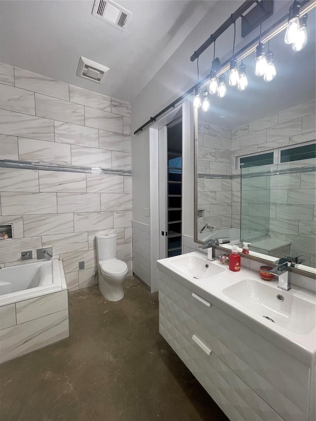 bathroom featuring toilet, a relaxing tiled tub, concrete floors, tile walls, and vanity