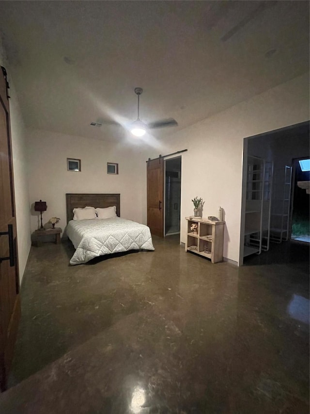 bedroom featuring ceiling fan, a barn door, and concrete flooring