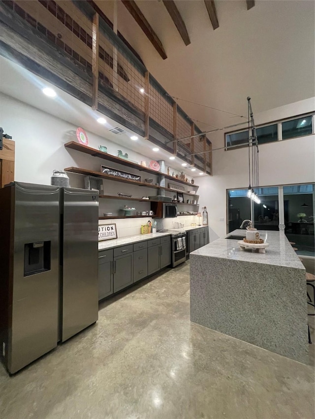 kitchen with a high ceiling, light stone countertops, pendant lighting, and stainless steel appliances