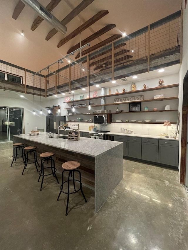 kitchen featuring light stone countertops, a towering ceiling, stainless steel appliances, and concrete flooring