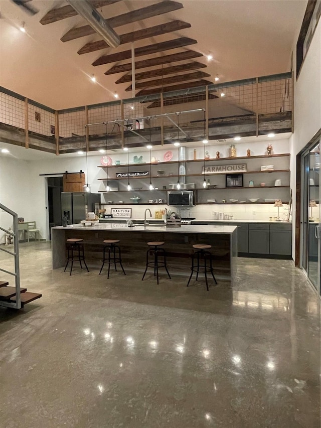 kitchen featuring appliances with stainless steel finishes, sink, a high ceiling, and a breakfast bar area