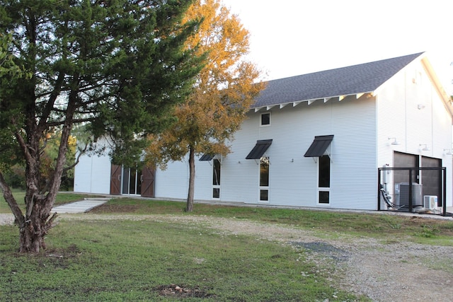 view of side of property with a yard and central AC