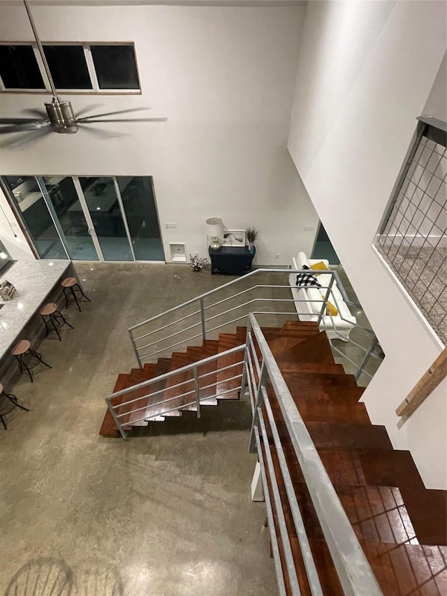 stairs featuring ceiling fan and concrete floors