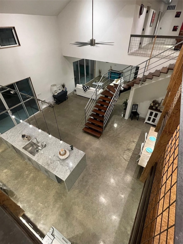 unfurnished living room featuring ceiling fan and a high ceiling