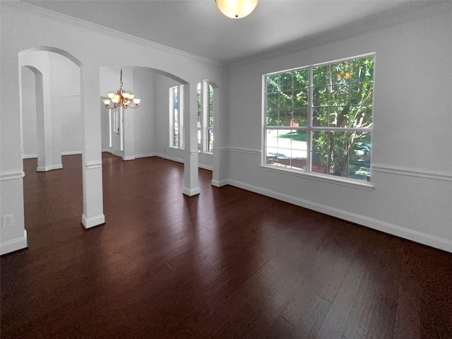 unfurnished room featuring ornate columns, crown molding, dark wood-type flooring, and a notable chandelier