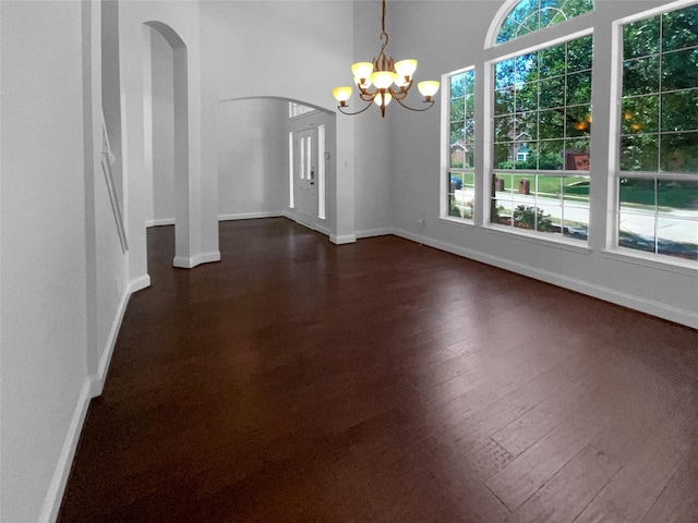 unfurnished room with an inviting chandelier and dark hardwood / wood-style flooring