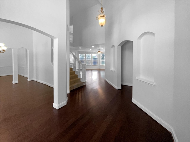 entrance foyer with dark hardwood / wood-style flooring, a towering ceiling, and ceiling fan