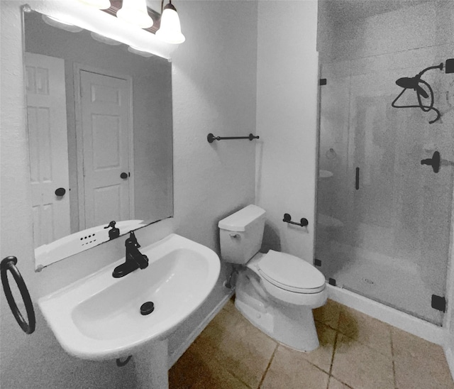 bathroom with tile patterned floors, toilet, sink, and a tile shower