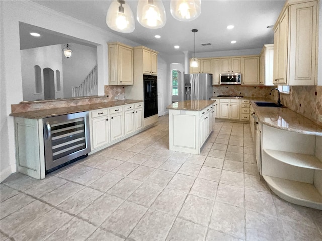 kitchen with sink, stainless steel appliances, a center island, decorative light fixtures, and beverage cooler